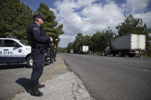 Police guard trucks loaded with avocados on their way to the city of Uruapan in Santa Ana Zirosto, Michoacan state, Mexico, Jan. 26, 2023. (AP Photo/Armando Solis, File)