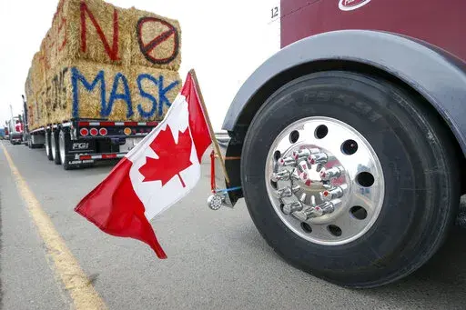 The Canadian flag is reflected in a wheel hub as anti-COVID-19 vaccine mandate demonstrators gather as a truck convoy blocks the highway at the busy U.S. border crossing in Coutts, Alberta, Canada, Monday, Jan. 31, 2022.   Thousands of antivaccine protesters descended on Canada’s capital of Ottawa in frigid temperatures to protest vaccine mandates, masks and restrictions over the weekend and some remain, blocking traffic around Parliament Hill in what has been the biggest pandemic protest in t
