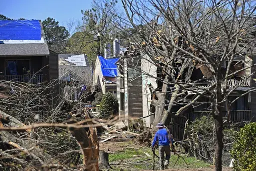 A man drags tree limbs to a pile at the Foxcroft Woods Condominiums, Sunday, April 2, 2023, in Little Rock, Ark. Residents across a wide swath of the U.S. raced to assess the destruction from fierce storms that spawned possibly dozens of tornadoes from the South and the Midwest into the Northeast, killing at least 32 people. (Staci Vandagriff/Arkansas Democrat-Gazette via AP)