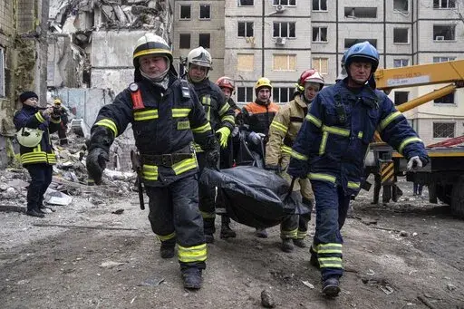 Rescue workers carry the body of a man who was killed in a Russian missile strike on an apartment building in the southeastern city of Dnipro, Ukraine, Monday, Jan. 16, 2023. (AP Photo/Evgeniy Maloletka)