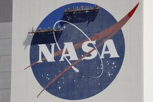 Workers on scaffolding repaint the NASA logo near the top of the Vehicle Assembly Building at the Kennedy Space Center in Cape Canaveral, Fla., Wednesday, May 20, 2020. After a yearlong study into UFOs, NASA is releasing a report Thursday, Sept. 14, 2023, on what it needs to better understand unidentified flying objects from a scientific point of view. (AP Photo/John Raoux, File)