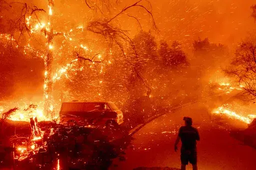 Bruce McDougal watches embers fly over his property as the Bond Fire burns through the Silverado community in Orange County, Calif., on Dec. 3, 2020. The United Nations on Monday, Feb. 28, 2022, released a new report on climate change. (AP Photo/Noah Berger, File)