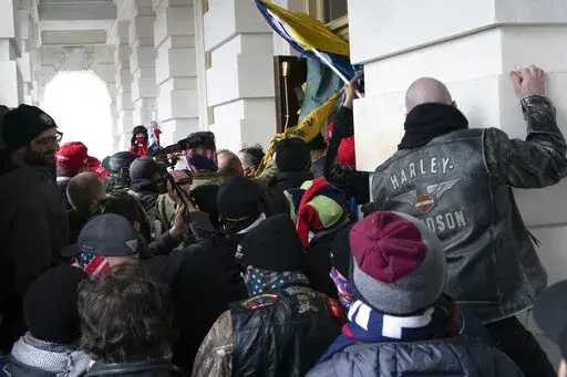 Insurrectionists loyal to President Donald Trump try to open a door of the U.S. Capitol as they riot in Washington, Jan. 6, 2021. Three active-duty Marines have been charged in the riot at the U.S. Capitol. Court records show that Micah Coomer, Joshua Abate and Dodge Dale Hellonen were arrested this week on misdemeanor charges after fellow Marines helped investigators identify them in footage among the pro-Trump mob on Jan. 6, 2021. (AP Photo/Jose Luis Magana, File)