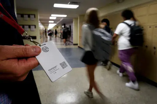 Brent Kiger, Olathe Public Schools' director of safety service, displays a panic-alert button while students at Olathe South High School rush between classes, Aug. 19, 2022, in Olathe, Kan. The district introduced the buttons, which allow staff to trigger a lockdown that will be announced with flashing strobe lights, a takeover of staff computers and a prerecorded intercom announcement, at the start of this school year as part of $2.1 million plan to make district schools more secure. In the wak