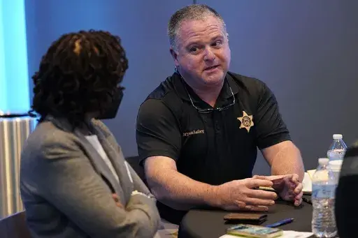 Rankin County Sheriff Bryan Bailey, right, speaks to an attendee at an employer engagement forum in Jackson, Miss., Nov. 4, 2021. Bailey, the Mississippi sheriff who leads the department where former deputies pleaded guilty to a long list of state and federal charges for the racist torture of two Black men has asked a federal court to dismiss a civil lawsuit against him, Friday, Oct. 6, 2023. (AP Photo/Rogelio V. Solis, File)