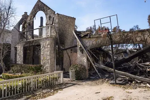 A basketball is stuck in the net outside of a residence destroyed by the Palisades Fire in the Pacific Palisades neighborhood of Los Angeles, Friday, Jan. 24, 2025. (AP Photo/Damian Dovarganes)