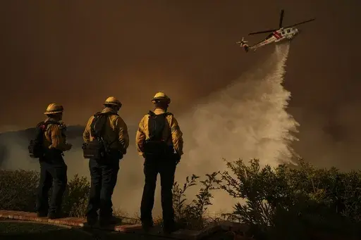 Water is dropped by helicopter on the Palisades Fire in Mandeville Canyon, Jan. 11, 2025, in Los Angeles. (AP Photo/Eric Thayer,File)
