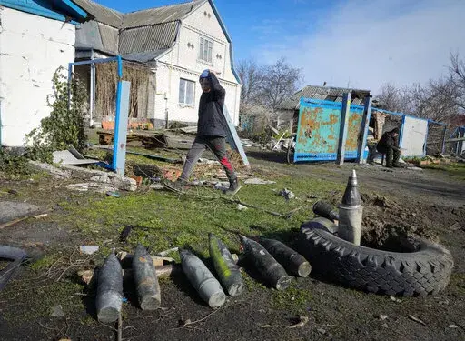 A boy walks by unexploded Russian shells in the village of Andriyivka close to Kyiv, Ukraine, Monday, April 11, 2022. Andriyivka was occupied by the Russian troops at the beginning of the Russia-Ukraine war and freed recently by the Ukrainian army. (AP Photo/Efrem Lukatsky)