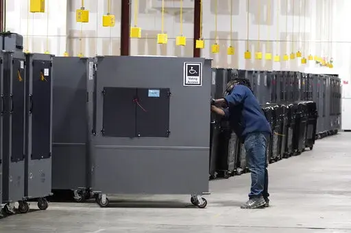 A worker returns voting machines to storage at the Fulton County Election preparation Center on Nov. 4, 2020 in Atlanta, Ga. The list of security breaches at local election offices since the 2020 election keeps growing, with investigations ongoing in at least three states, Colorado, Georgia and Michigan. Security experts say the breaches by themselves have not necessarily increased threats to the November elections, but say they increase the possibility that rogue election workers could access e