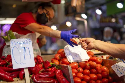 A customer pays for vegetables at the Maravillas market in Madrid, on May 12, 2022. Inflation figures for Europe will be released Friday, July 1, 2022, as Russia's war in Ukraine has worsened the worldwide surge in consumer prices. For months, inflation in the 19 countries that use the euro has risen at the fastest pace since record-keeping for the currency began. (AP Photo/Manu Fernandez, File)