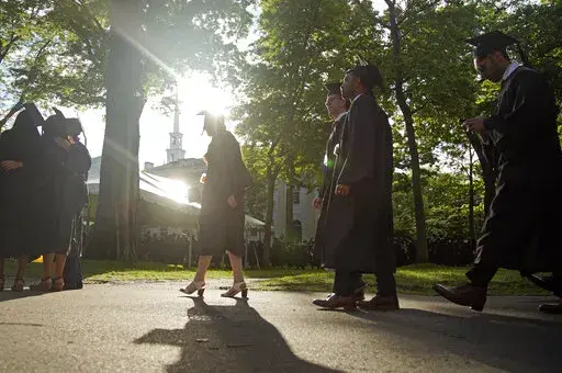 Graduates walk at a Harvard Commencement ceremony held for the classes of 2020 and 2021, Sunday, May 29, 2022, in Cambridge, Mass. The Department of Education says borrowers who hold eligible federal student loans and have made voluntary payments since March 13, 2020, can get a refund. (AP Photo/Mary Schwalm)