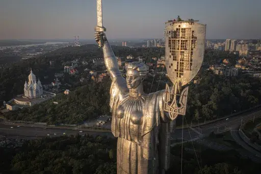 Workers install the Ukrainian coat of arms on the shield in the hand of the country's tallest stature, the Motherland Monument, after the Soviet coat of arms was removed, in Kyiv, Ukraine, Sunday, Aug. 6, 2023. Ukraine is accelerating efforts to erase the vestiges of centuries of Soviet and Russian influence from the public space amid the Russian invasion of Ukraine by pulling down monuments and renaming hundreds of streets to honor home-grown artists, poets, military chiefs, and independence le