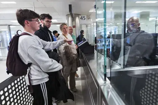 Piet De Staercke, from back right to left, with his wife Jill Bornauw, their eldest son Stan De Staercke, watch their youngest Tuur de Staercke, get screened by a Custom Border Protection officer, right, in the port of entry at Washington Dulles International Airport in Chantilly, Va. Monday, April 1, 2024. The Belgian family of four, used the Mobile Passport Control app, the newest technology in international travel, to ease their way to their port of entry. Within minutes they had bypassed a l