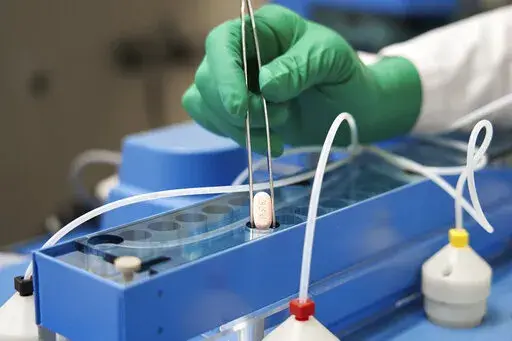 In this photo provided by Pfizer, a technician handles one of the company's COVID-19 Paxlovid pills. COVID-19 patients have two new treatment options that can be taken at home. But that convenience comes with a catch: The pills have to be taken as soon as possible once symptoms appear. U.S. regulators authorized the pills from Pfizer and Merck late 2021. (Pfizer via AP, File)