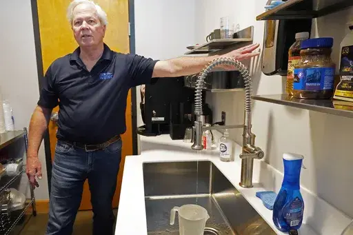 Ted Henifin, interim water manager for JXN Water, the water system for the city of Jackson, Miss., demonstrates how to run faucet water like a "thin line of spaghetti with intermittent breaks" in order to deal with expected below freezing weather, at a news conference in Jackson, Miss., Friday, Jan. 12, 2024. Law enforcement agencies are investigating whether social media rumors about a potential water outage prompted people to quickly fill containers with tap water in Mississippi's capital duri