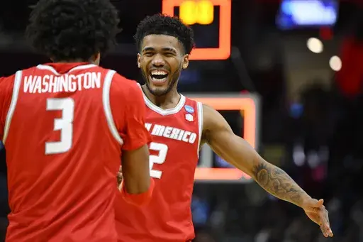 New Mexico guards Tru Washington (3) and Donovan Dent (2) celebrate after a win over Marquette in the first round of the NCAA college basketball tournament, Friday, March 21, 2025, in Cleveland. (AP Photo/David Richard)