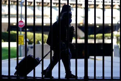 Travelers wear mask as they walk to a parking lot at O'Hare International Airport in Chicago, Friday, July 2, 2021.  Demand for travel has returned to pre-pandemic levels just in time for travel’s hottest season — summer. National parks, Mexico and other resort destinations have surging demand, making them less-than-ideal destinations for budget-conscious travelers. Instead, deal seekers should go to places that have been slow to recover, such as Italy and Greece.   (AP Photo/Nam Y. Huh, Fil
