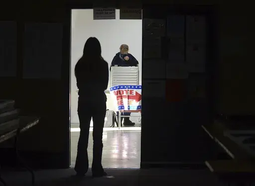 A first-time voter waits in the doorway for a voting booth as another voter completes his ballot at the Boot City Opry near Terre Haute, Ind., Nov. 3, 2020. (Joseph C. Garza/The Tribune-Star via AP, File)
