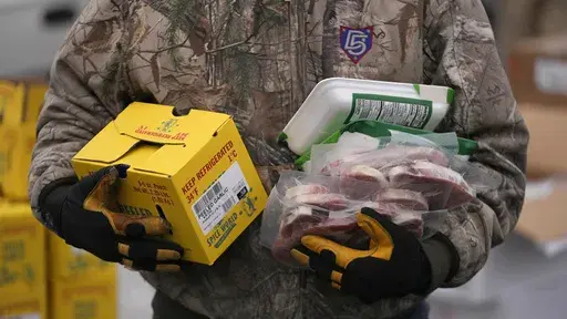 A Utah Food Bank volunteer carries groceries for the needy at a mobile food pantry distribution site Wednesday, Dec. 21, 2022, in Salt Lake City. The end of the calendar year is when nonprofits make appeals far and wide to attract donors — in part because of holiday traditions or, for some, tax advantages. (AP Photo/Rick Bowmer, File)