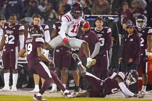 Mississippi wide receiver Dontario Drummond (11) leaps over fallen Mississippi safety Jalen Green for a first down during the first half of an NCAA college football game Thursday, Nov. 25, 2021, in Starkville, Miss. (AP Photo/Rogelio V. Solis)