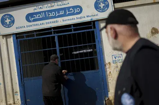 Dr. Mohammad Fares, right, watches a man close the Sarmada Health Center, in Sarmada district, north of Idlib city, Syria, Sunday, Feb. 9, 2025. (AP Photo/Ghaith Alsayed)