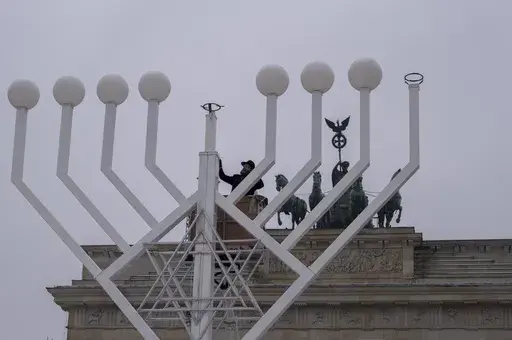 Rabbi Yehuda Teichtal, center, inspects a giant Hanukkah Menorah, set up by the Jewish Chabad Educational Center ahead of the Jewish Hanukkah holiday, in front of the Brandenburg Gate at the Pariser Platz in central Berlin, Germany, Wednesday, Dec. 6, 2023. Holocaust survivors from around the globe will mark the start of the fifth day of Hanukkah together with a virtual ceremony as worries grow among Jews worldwide about the Israel-Hamas war and a spike of antisemitism in Europe, the United Stat