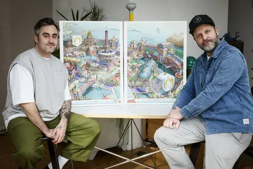 CORRECTS SPELLING OF FIRST NAME FROM HUGO TO UGO - French artist Ugo Gattoni, left, and head of design for Paris 2024, Joachim Roncin pose next to the Paris 2024 Olympic and Paralympic posters in Ivry-sur-Seine outside Paris, Tuesday Feb. 20, 2024. Vibrant colors and striking landmarks illuminate posters for the Paris Olympic Games in an Art Deco style inspired by the city's flamboyant past. The posters have been unveiled at the Musée d'Orsay. (AP Photo/Thomas Padilla)