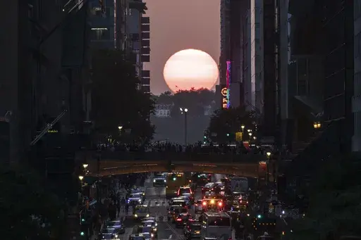 FILE — The sun sets between buildings along 42nd Street in New York during a phenomenon known as Manhattanhenge, May 30, 2023. Wednesday, July 12, 2023, and Thursday, July 13, 2023 are the last two days of Manhattanhenge for the year, when jaded New Yorkers spill onto the streets to watch the sun set between the buildings that line the city's east-west corridors. But the forecast calls for clouds so there may not be much of a show. (AP Photo/Yuki Iwamura, File)