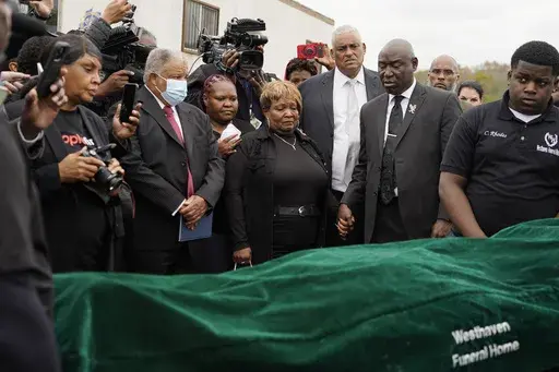 Civil rights attorney Ben Crump, center right, Bettersten Wade, center, mother of Dexter Wade, a 37-year-old man who died after being hit by a Jackson, Miss., police SUV driven by an off-duty officer, watches her son's body transferred to a mortuary transport after being exhumed from a pauper's cemetery near the Hinds County Penal Farm in Raymond, Monday, Nov. 13, 2023. After men in near Mississippi's capital were buried in a pauper’s cemetery without their relatives’ knowledge, the U.S. Jus
