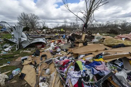 People walk through damage from a late-night tornado in Sullivan, Ind., April 1, 2023. (AP Photo/Doug McSchooler, File)