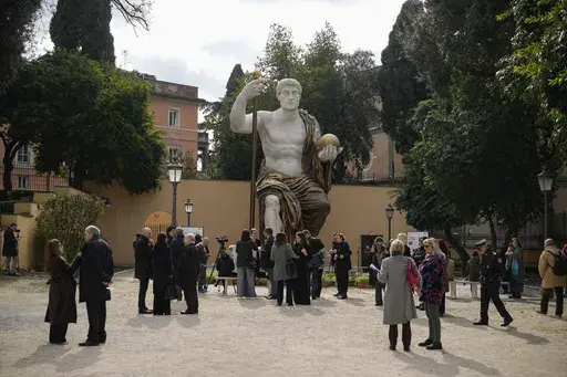 Visitors admire a massive, 13-meter (yard) replica of the statue Roman Emperor Constantine commissioned for himself after 312 AD that was built using 3D technology from scans of the nine giant original marble body parts that remain, as it was unveiled in Rome, Tuesday, Feb. 6, 2024. The imposing figure of a seated emperor, draped in a gilded tunic and holding a scepter and orb, gazing out over his Rome, is located in a side garden of the Capitoline Museums, just around the corner from the courty