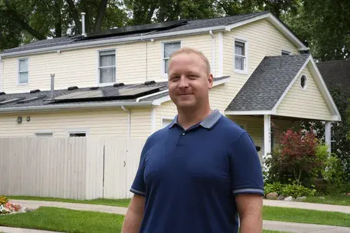 Jason Benedict poses with solar panels on his home in Berkley, Mich., Wednesday, July 24, 2024. (AP Photo/Paul Sancya)