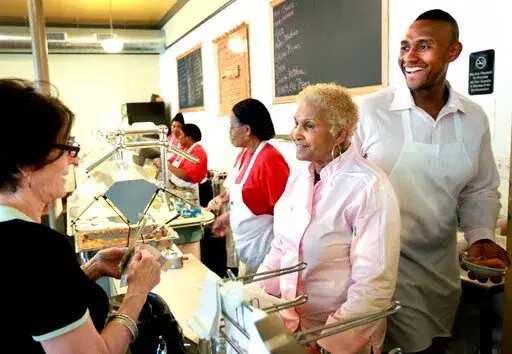 A customer picks up some to go food from Sweetie Pie's owner Robbie Montgomery, center, and Montgomery's son James "Tim" Norman, right, at Sweetie Pie's in St. Louis, on April 19, 2011. Norman, former star of “Welcome to Sweetie Pie's” reality TV show, testified Tuesday, Sept. 13, 2022, that he was not involved in the murder of his nephew. Norman is accused of hiring two people to kill 21-year-old Andre Montgomery in March 2016 and then trying to cash a $450,000 life insurance policy he took