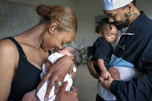 Aaliyah Wright, 25, of Washington, nuzzles her newborn daughter Kali, as her husband Kainan Wright, 24, of Washington, holds their son Khaza, 1, as he falls asleep, during a visit to the children's grandmother in Accokeek, Md., Tuesday, Aug. 9, 2022. A landmark social program is being pioneered in the nation’s capital. Coined “Baby Bonds,” the program is designed to narrow the wealth gap. The program would provide children of the city’s poorest families up to $25,000 when they reach adul