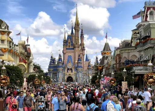 Crowds fill Main Street USA in front of Cinderella Castle at the Magic Kingdom on the 50th anniversary of Walt Disney World, in Lake Buena Vista, Fla., on Oct. 1, 2021. Facing backlash, Walt Disney World’s governing district will pay a stipend to employees whose free passes and discounts to the theme park resort were eliminated under a policy made by a new district administrator and board members who are allies of Florida Gov. Ron DeSantis. (Joe Burbank/Orlando Sentinel via AP, File)
