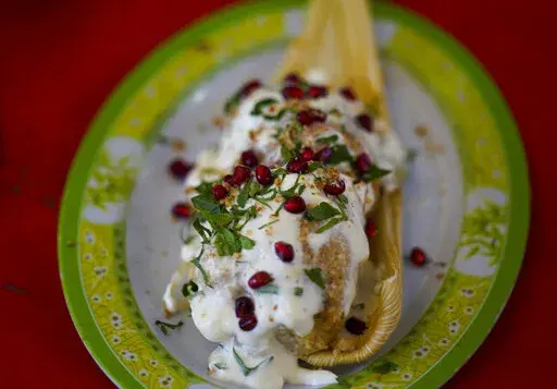 A Chiles en Nogada style tamal is displayed during the tamales fair at the Ixtapalapa neighborhood of Mexico City, Friday, Jan. 27, 2023. Chiles en nogada is a Mexican dish of poblano chiles stuffed with picadillo topped with a walnut-based cream sauce called nogada, pomegranate seeds and parsley, and it is typically served at room temperature. It is widely considered a national dish of Mexico. (AP Photo/Fernando Llano)