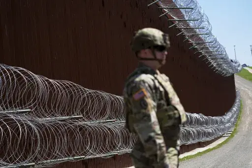 A member of the military looks on in front of newly-installed concertina wire lining one of two border walls separating Mexico from the United States during a news conference on joint operations involving the military and the Border Patrol, March 21, 2025, in San Diego. (AP Photo/Gregory Bull, File)