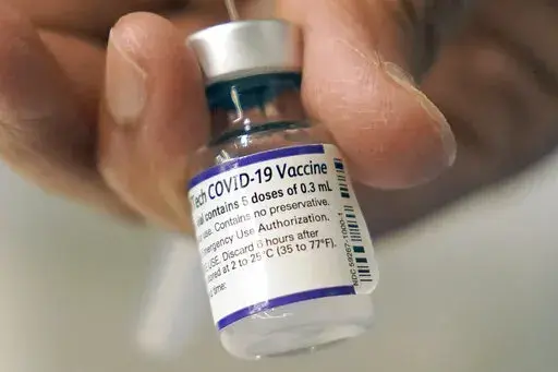 A doctor loads a dose of Pfizer COVID-19 vaccine into a syringe, Thursday, Dec. 2, 2021, at a mobile vaccination clinic in Worcester, Mass. In January 2022, an influential government advisory panel is considering COVID-19 boosters for younger teens, as the U.S. battles the omicron surge and schools struggle with how to restart classes amid the spike. (AP Photo/Steven Senne, File)