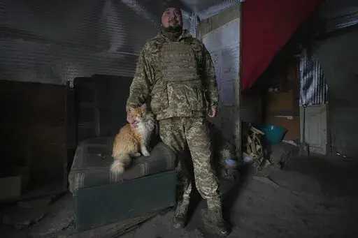 An Ukrainian serviceman pats Vasiliy the cat at an advanced position on the front line in the Luhansk area, eastern Ukraine, Thursday, Jan. 27, 2022. The U.S. rejection of Russia's main demands to resolve the crisis over Ukraine left "little ground for optimism," the Kremlin said Thursday, but added that dialogue was still possible. (AP Photo/Vadim Ghirda)