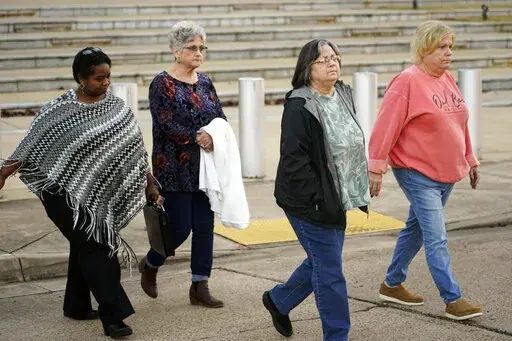 Wanda Farris, the mother of slain teenager Leesa Gray, second from right, is surrounded by supporters as she leaves the federal courthouse in Jackson, Miss., on Monday, Nov. 28, 2022, after they listened to several hours of arguments about Mississippi's three-drug protocol for executions. Thomas Edwin Loden Jr. pleaded guilty in 2001 to capital murder, rape and four counts of sexual battery in the 2000 death of Gray, a 16-year-old waitress from north Mississippi. Loden is a plaintiff in the laws