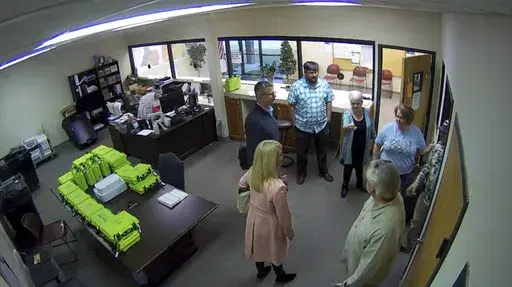 This Jan. 7, 2021, image taken from Coffee County, Ga., security video, appears to show Cathy Latham (center, long turquoise top), introducing members of a computer forensic team to local election officials. Latham was the county Republican Party chair at the time. The computer forensics team was at the county elections office in Douglas, Ga., to make copies of voting equipment in an effort that documents show was arranged by attorney Sidney Powell and others allied with then-President Donald Tr