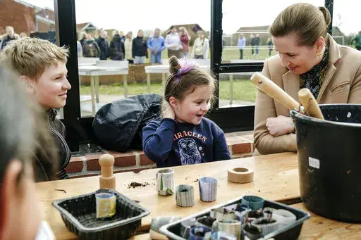 Danish Prime Minister Mette Frederiksen, right, meets Ukrainian refugee children at Paradisbakken school in Nexoe, as she visits the island of Bornholm in Denmark, Thursday, April 7, 2022. Anna Prokopiuk, center,  is from Ukraine but has lived in Denmark for three years and is therefore able to help interpret for the newly arrived refugees. (Pelle Rink/Ritzau Scanpix via AP)