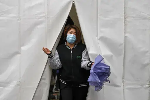A woman wearing a face mask to help protect from the coronavirus walks out from a tent after getting a COVID-19 test, Tuesday, March 29, 2022, in Beijing. A two-phase lockdown of Shanghai's 26 million people is testing the limits of China's hard-line "zero-COVID" strategy, which is shaking markets far beyond the country's borders. (AP Photo/Andy Wong)