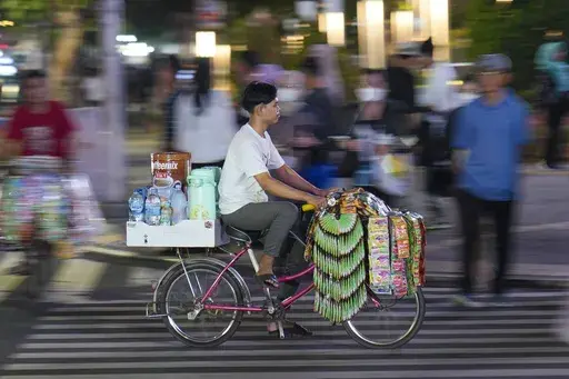 A 'Starlings' bicycle coffee seller, an abbreviation for Starbucks Keliling or mobile Starbucks, rides on a busy street at the main business district in Jakarta, Indonesia, Wednesday, Oct. 2, 2024. (AP Photo/Tatan Syuflana)