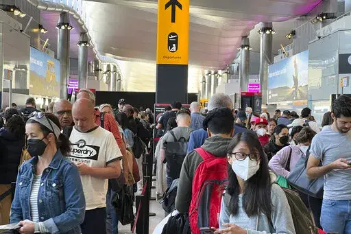 Travellers queue at security at Heathrow Airport in London, Wednesday, June 22, 2022. London’s Heathrow Airport  apologized Monday, July 11, 2022 to passengers whose travels have been disrupted by staff shortages. The airport warned that it may ask airlines to cut more flights from their summer schedules to reduce the strain if the chaos persists. (AP Photo/Frank Augstein, File)