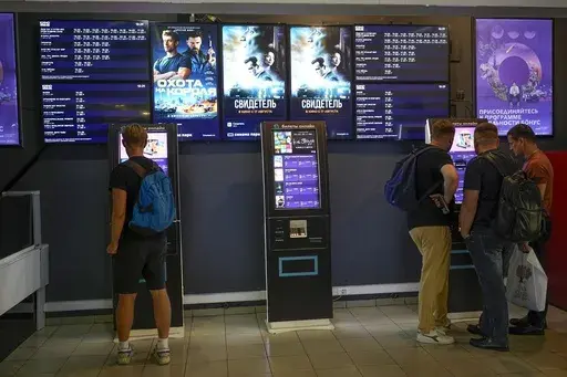 People stand at ticket machines in a cinema lobby inside a shopping mall in Moscow, Russia, Thursday, Aug. 17, 2023. "The Witness," a state-sponsored drama that premiered in Russia on Aug. 17, is the first feature film about Russia's military campaign in Ukraine to hit the movie theaters nationwide. It depicts Ukrainian troops as violent neo-Nazis who torture and kill their own people. (AP Photo/Alexander Zemlianichenko)