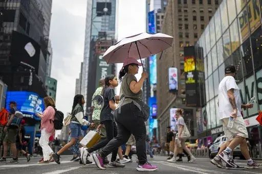 A pedestrian uses an umbrella to shield against the sun while passing through Times Square as temperatures rise, July 27, 2023, in New York. At about summer's halfway point, the record-breaking heat and weather extremes are both unprecedented and unsurprising, hellish yet boring in some ways, scientists say. (AP Photo/John Minchillo, File)