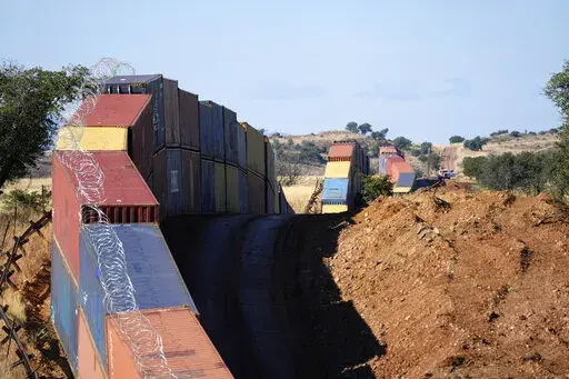 A long row of double-stacked shipping contrainers provide a new wall between the United States and Mexico in the remote section area of San Rafael Valley, Ariz., Thursday, Dec. 8, 2022. Work crews are steadily erecting hundreds of double-stacked shipping containers along the rugged east end of Arizona’s boundary with Mexico as Republican Gov. Doug Ducey makes a bold show of border enforcement even as he prepares to step aside next month for Democratic Governor-elect Katie Hobbs. (AP Photo/Ross