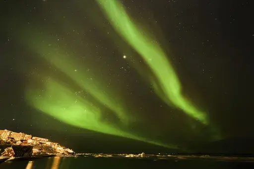 The northern lights appear over homes in Nuuk, Greenland, Monday, Feb. 17, 2025. (AP Photo/Emilio Morenatti)