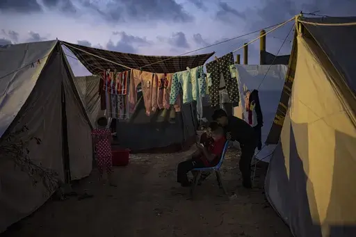 Palestinian kids, who were displaced by the Israeli bombardment of the Gaza Strip, watch a phone in a UNDP-provided tent camp in Khan Younis, Gaza Strip, Wednesday, Nov. 1, 2023. While journalists' access to the war in Gaza is limited, a flood of video from all sorts of sources documents what is — and isn't — going on. (AP Photo/Fatima Shbair, File)
